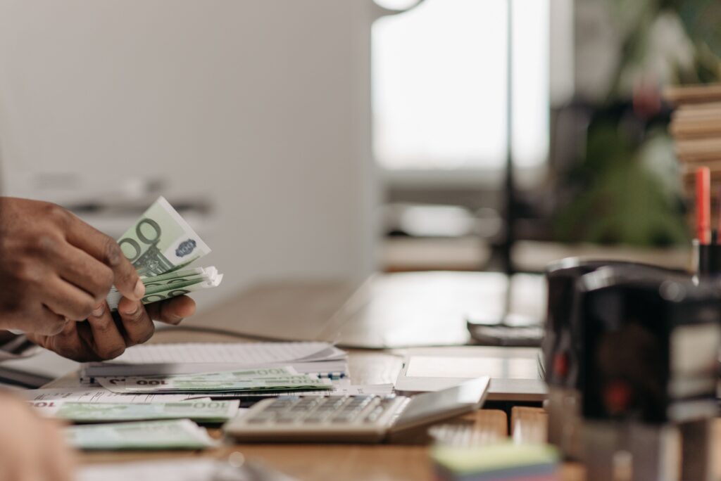 pexels photo 7654180 7654180 Close-up of hands counting euro bills at an office desk with a calculator.