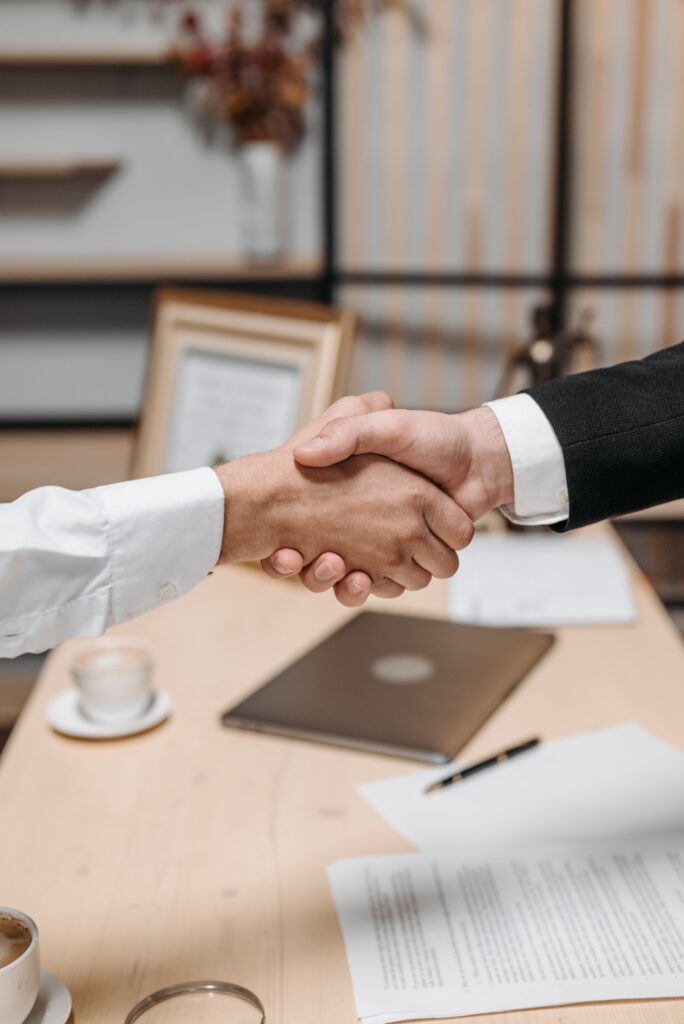 pexels photo 8112186 8112186 Close-up of two people shaking hands in an office, symbolizing agreement and partnership.